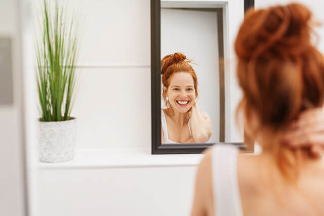 woman looks in mirror