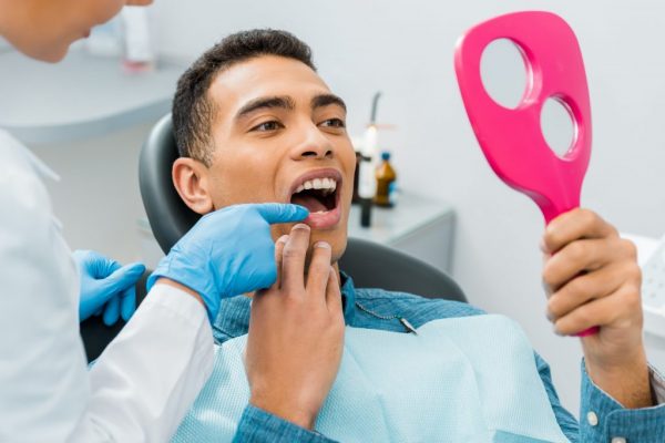 patient looking at teeth in hand mirror