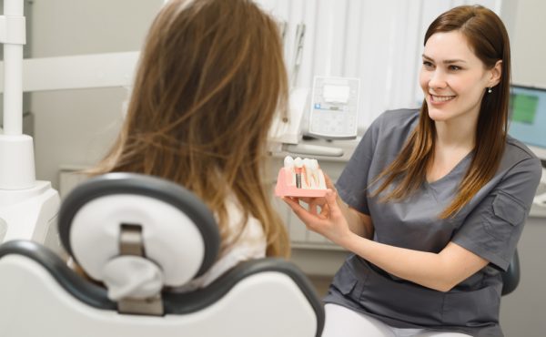 dentist showing patient model of dental implant