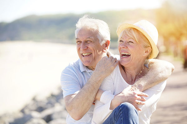 elderly couple laughing and smiling by a lake